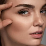 A woman pointing at her eyebrows