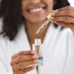 A woman holding a serum bottle