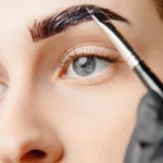 A woman applying eyebrow product